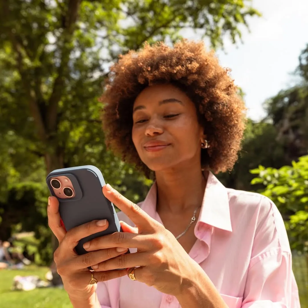 A customer smiling at an order update on her phone in a park