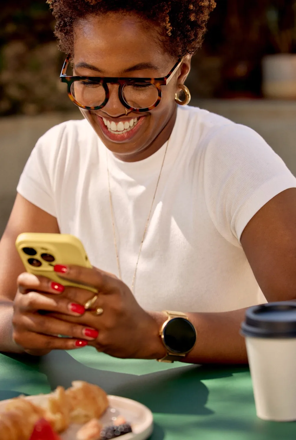 A customer smiling at a message on her phone over coffee