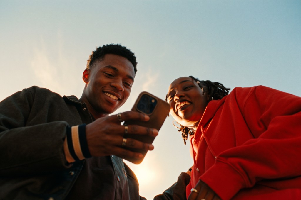 Two friends laughing together while looking at a phone